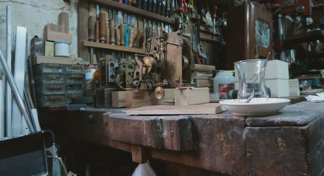 Intricate vintage clock mechanism on a cluttered carpenters workbench indoors.